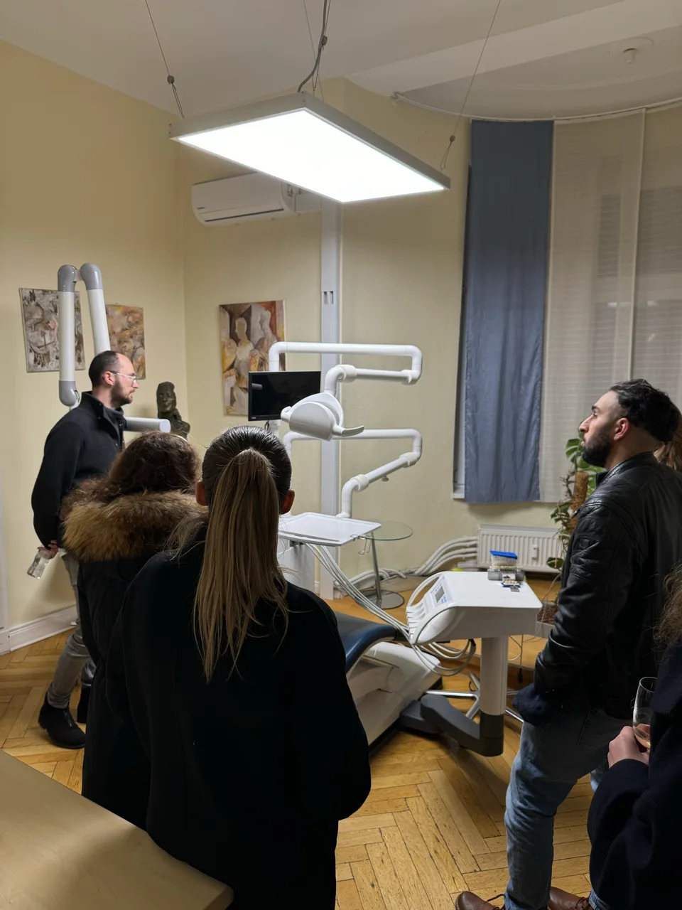 Gruppe hört bei einem Rundgang durch einen Behandlungsraum zu