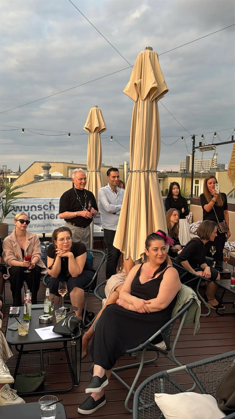 Team sitzt zwischen Sonnenschirmen auf der Dachterrasse und hört aufmerksam zu