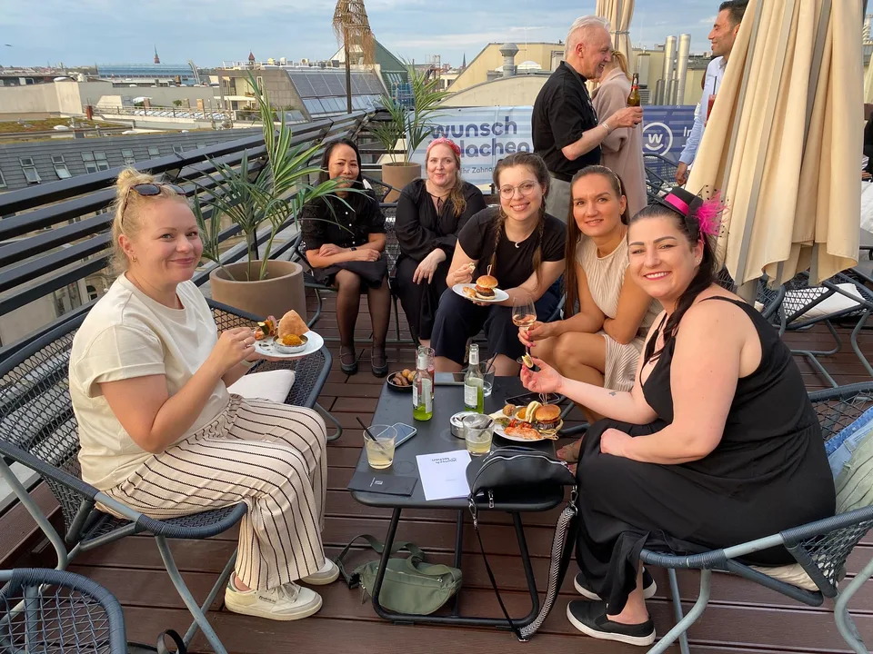 Kolleginnen mit Burgern am Tisch auf der Dachterrasse