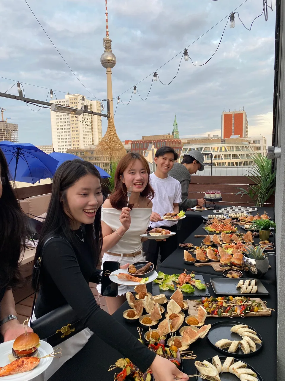 Kolleginnen und Kollegen lachen am Buffet vor dem Fernsehturm