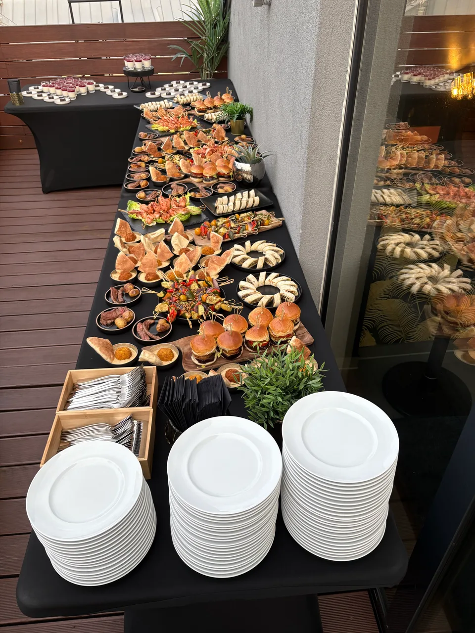 Langes Buffet mit Häppchen und Tellerstapeln auf der Terrasse
