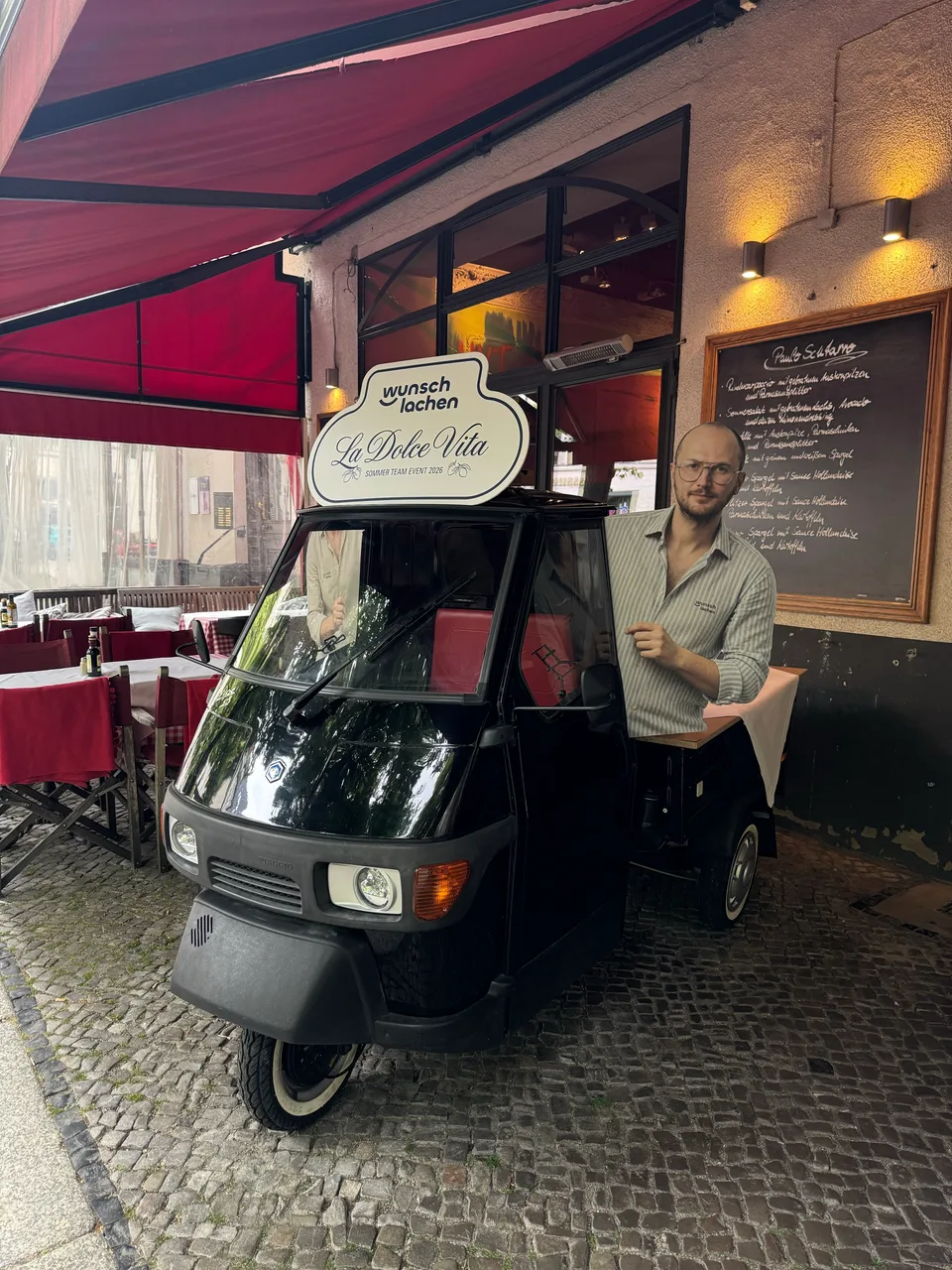Fotobox-Ape unter der roten Markise vor dem Restaurant
