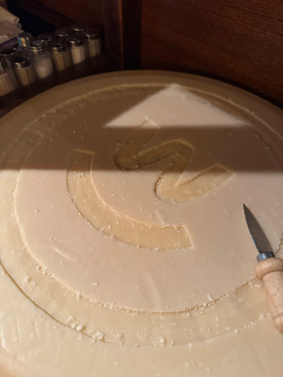 Parmesanlaib mit eingeritztem Logo und Käsemesser