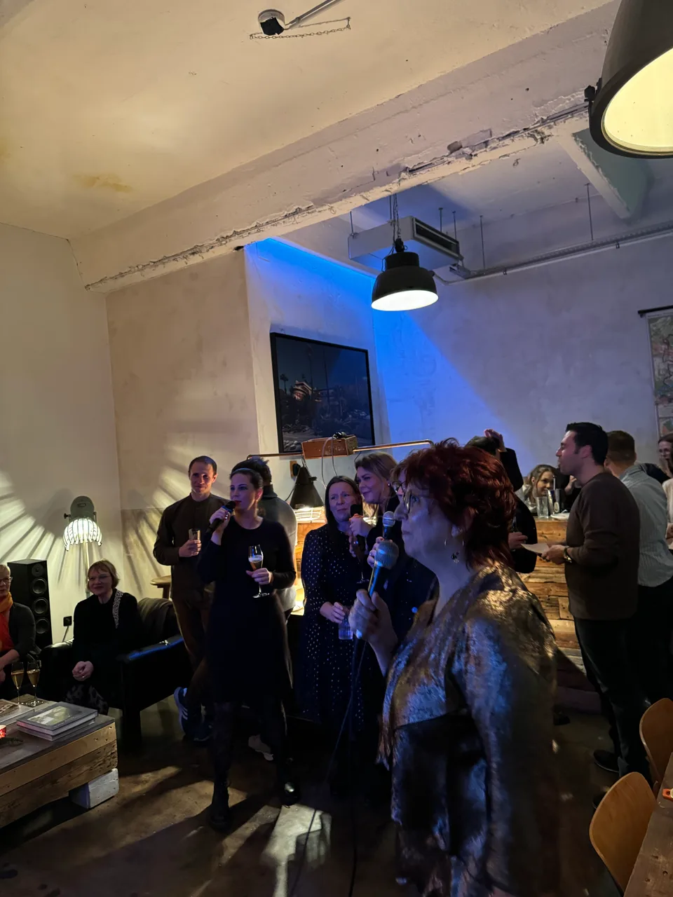 Kolleginnen mit Mikrofonen vor dem zuschauenden Team im Loft