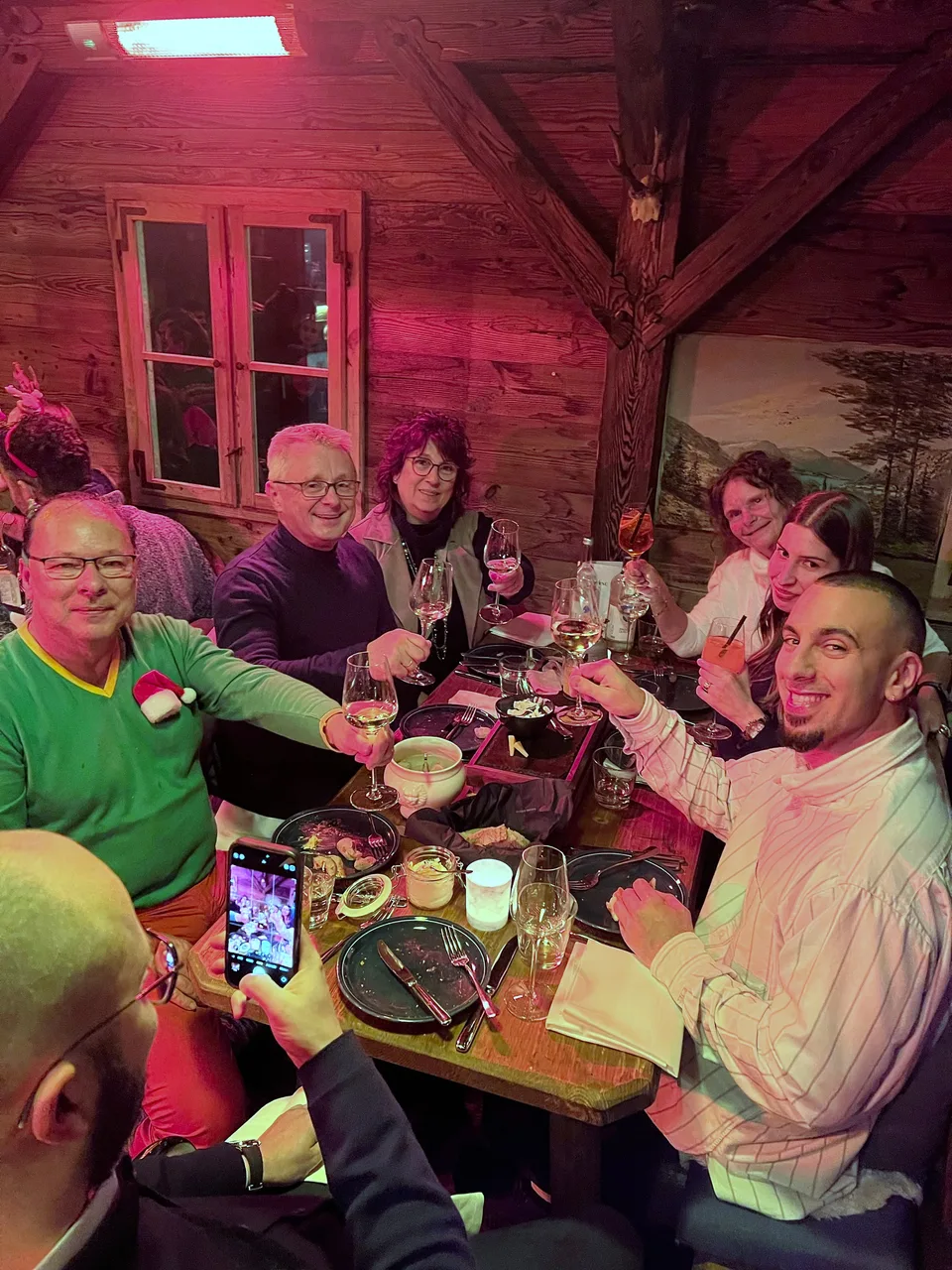 Kollegen stoßen am Tisch lächelnd miteinander an