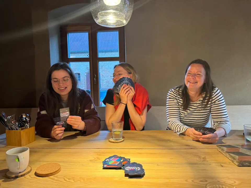 Kartenspiel am Holztisch mit lachenden Kolleginnen