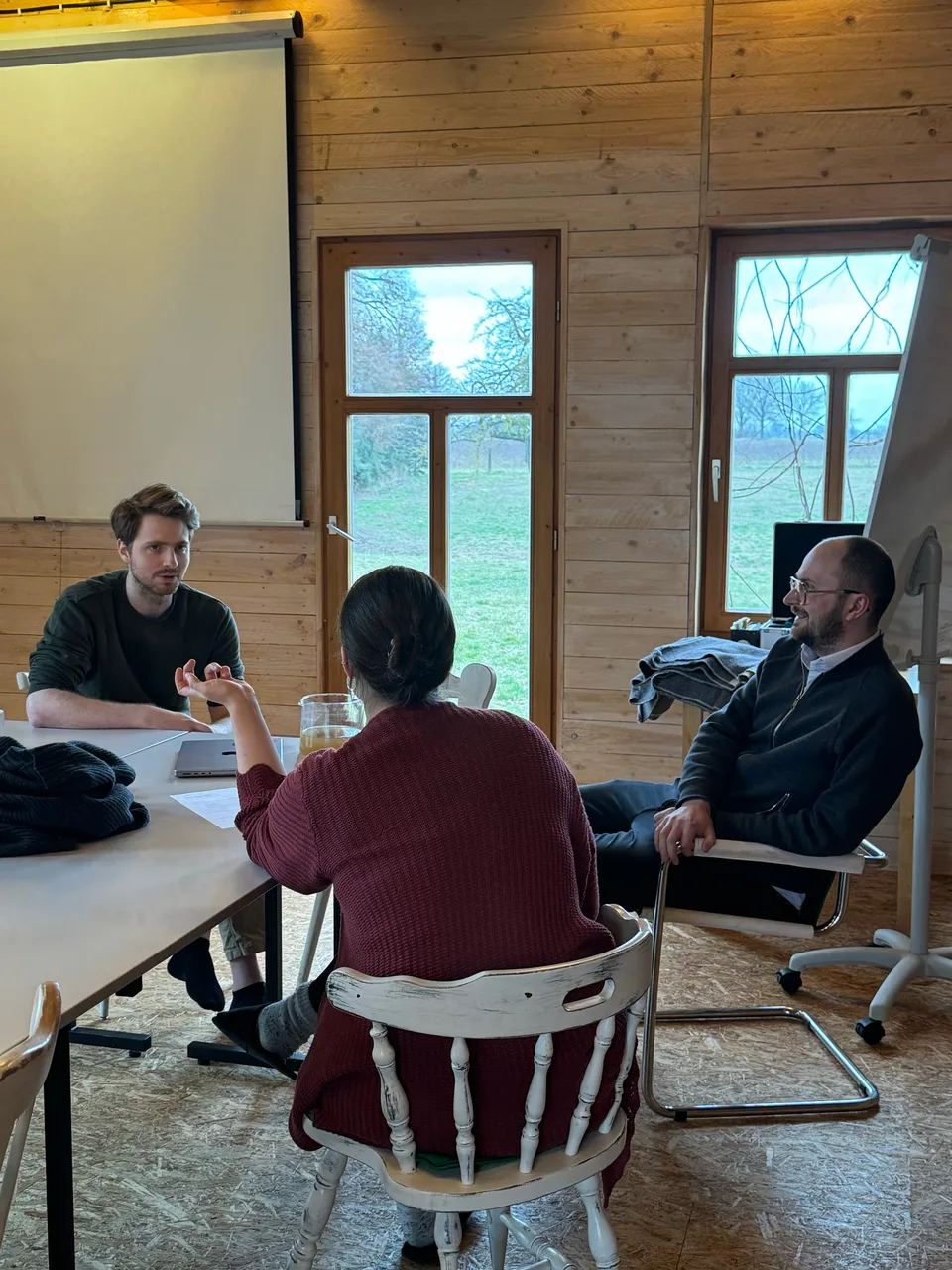 Gesprächsrunde zu dritt im holzvertäfelten Seminarraum