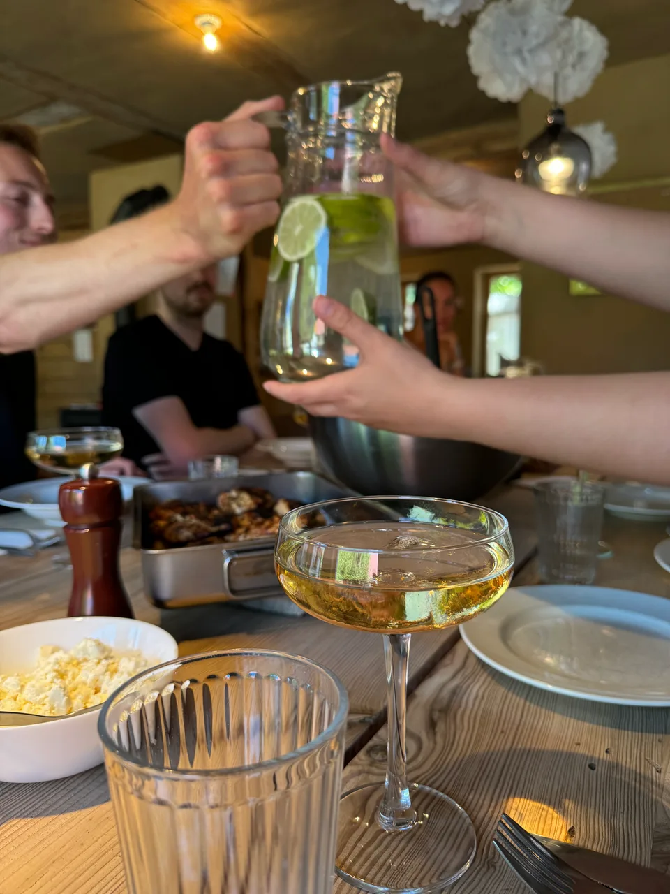 Anstoßen mit Gläsern und Karaffe am Esstisch