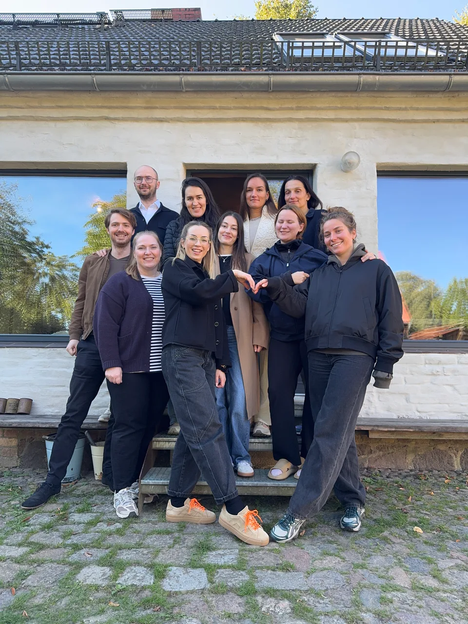 Gruppenbild mit Herz-Geste vor dem Haus