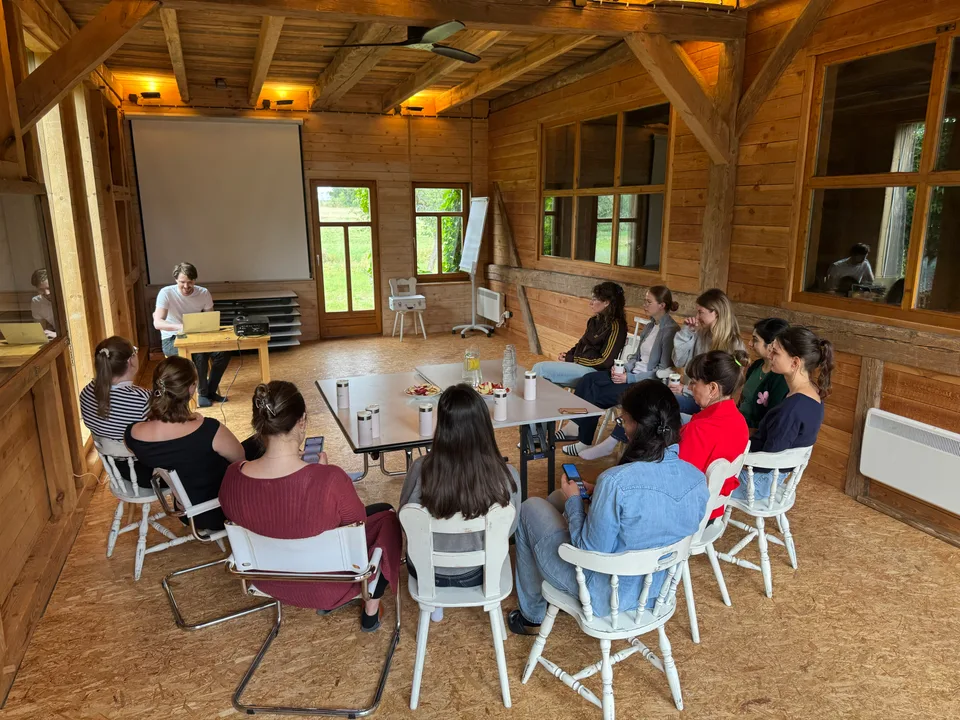 Workshoprunde im Stuhlkreis im hellen Holzbalkensaal