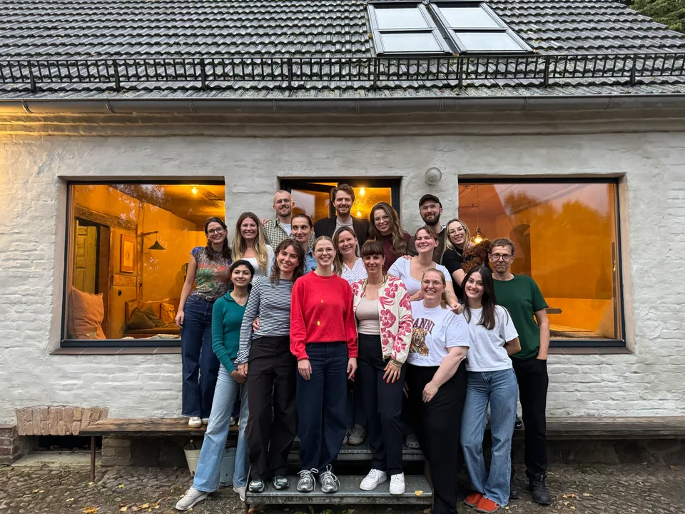 Gruppenbild des ganzen Teams vor dem beleuchteten Landhaus am Abend